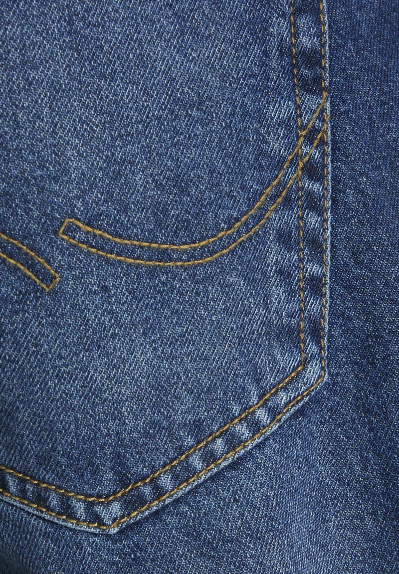 Niebieski materiał dżinsowy z tylną kieszenią z żółtym przeszyciem, zakrzywionymi akcentami i gładką teksturą.