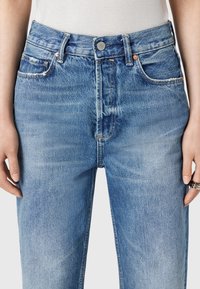 Jeans in denim azzurro chiaro con vita alta, dotati di cinque tasche, cuciture a vista e chiusura con bottone in vita.