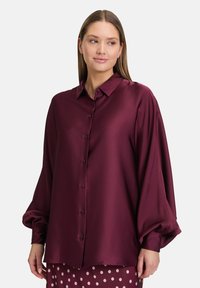 Burgundy satin blouse with a relaxed fit, long puff sleeves, a button-up front, and a classic collar. Smooth texture and elegant drape.