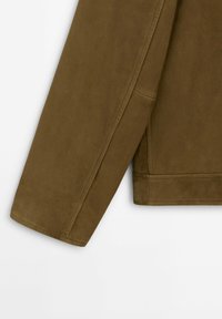 Manica di un giubbotto in tessuto sintetico marrone con una texture liscia, caratterizzata da una cucitura pulita e una vestibilità sartoriale, che termina al polso.