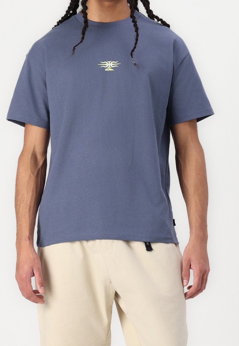 Light blue cotton t-shirt with short sleeves, featuring a small yellow graphic design on the chest and a black label at the hem.