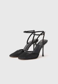 Sandali neri con tacco alto, con tomaia in rete, punte a forma appuntita, doppie cinghie alla caviglia e tacco a stiletto sottile. Fodera interna liscia.