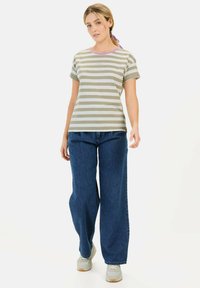 Lys olivengrøn og hvid stribet t-shirt med korte ærmer og en lilla krave, parret med brede blå jeans og grå sneakers.