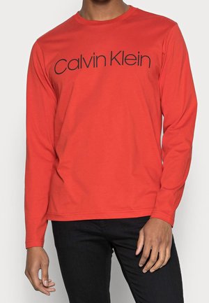 Rotes Langarm-T-Shirt aus Baumwolle mit Rundhalsausschnitt. Mit dem schwarzen "Calvin Klein"-Logo auf der Brust. Schlichtes Design, keine Muster.