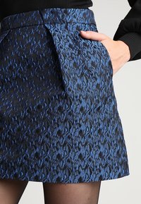Jupe bleue et noire à motifs avec un tissu texturé, dotée d'une taille cintrée, de poches latérales et d'un ourlet évasé.