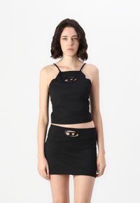 Black cropped top with thin straps featuring a cutout detail. Paired with a black mini skirt, both made from a smooth, stretchy fabric.
