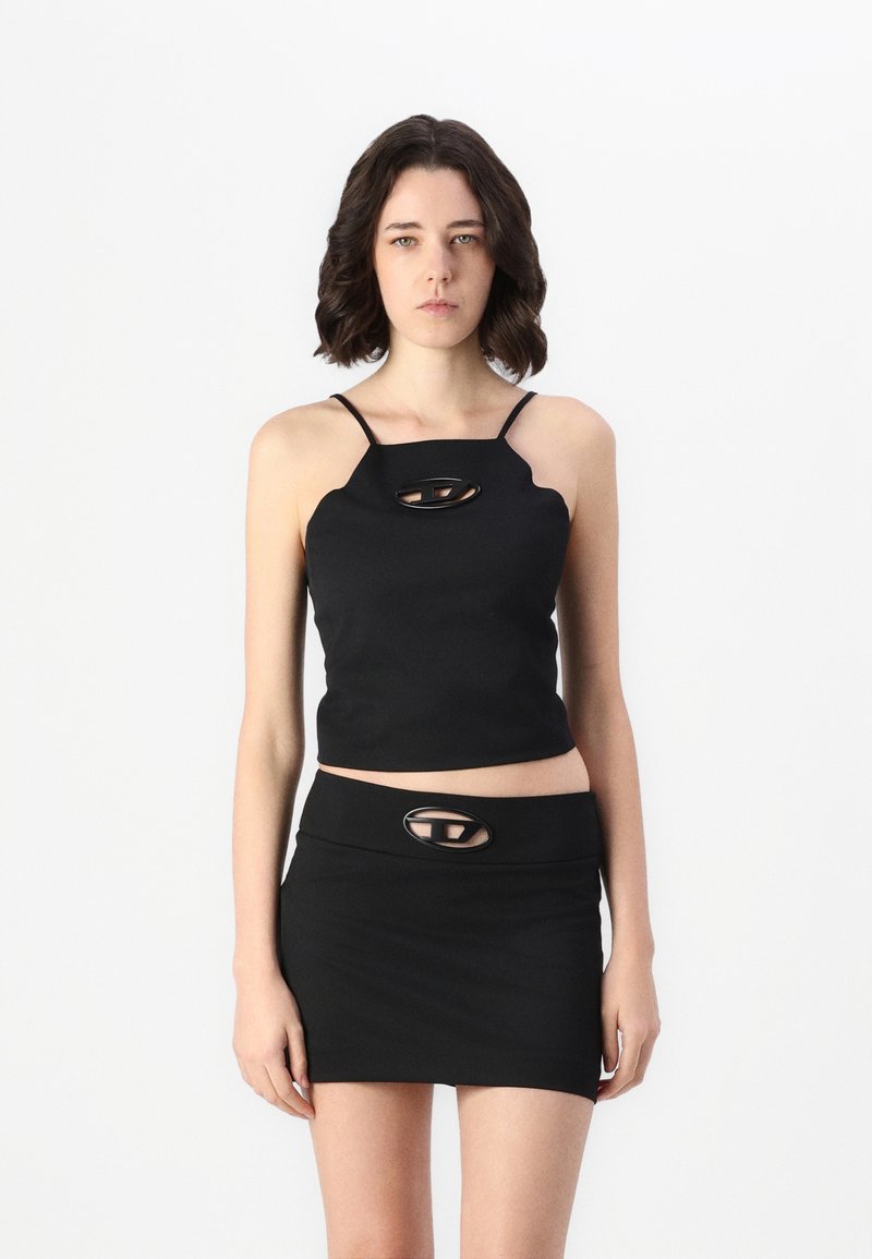 Black cropped top with thin straps featuring a cutout detail. Paired with a black mini skirt, both made from a smooth, stretchy fabric.