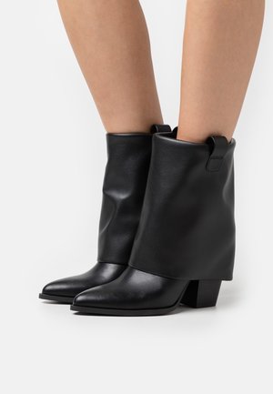 Stivaletti alla caviglia in pelle nera con punta appuntita, caratterizzati da un risvolto piegato e un tacco a blocco per la stabilità. Texture liscia, minimali dettagli metallici.