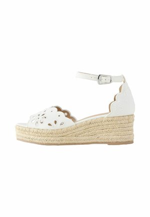 Sandale compensée espadrille blanche avec découpes florales festonnées et boucle sur bride de cheville sur semelle en jute tressée.