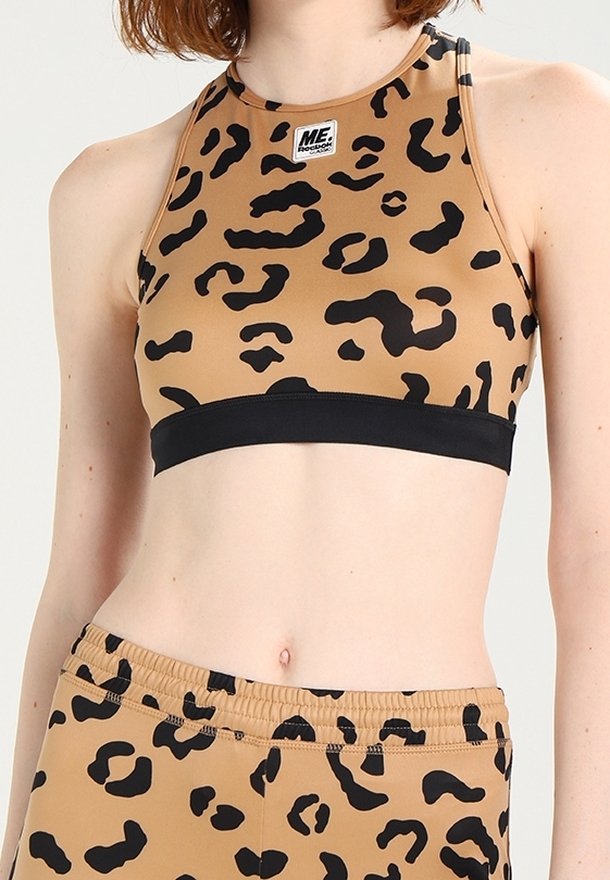Bruine sportbeha en shorts met zwart luipaardmotief gedragen op een blote buik.