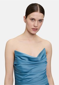 Trägerloses Kleid in einem satten Blauton, ausgestattet mit drapiertem Satin-Stoff mit sanften Falten, glatter Textur und einem strukturierten Design.