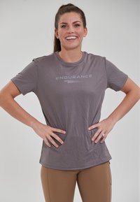 Kortærmet grå atletisk T-shirt med teksten "ENDURANCE" i en lysere grå skrifttype, lavet af et glat, fleksibelt stof med en afslappet pasform.