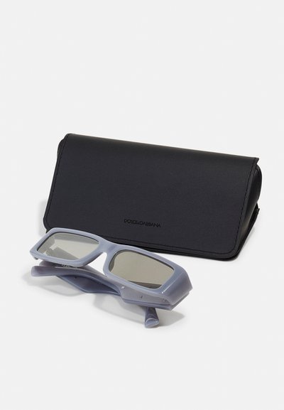 Occhiali da sole con montatura rettangolare blu chiaro, lenti grigie e dettagli in argento, accompagnati da un elegante astuccio in pelle nera.