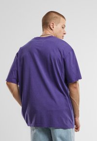 T-shirt oversized violet à manches courtes, en coton, col rond et coupe décontractée. Pas de motifs ni de marques visibles ; design uni.