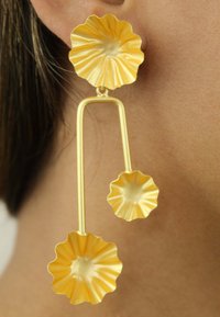 Guldtonade hängörhängen med två flikiga blomformer. Den övre blomman är större och kopplad med en slät båge till en mindre blomma nedan.