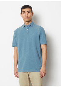 Blue polo shirt made of textured fabric, featuring a collar, two buttons, and a small logo on the chest. Short sleeves and standard fit.
