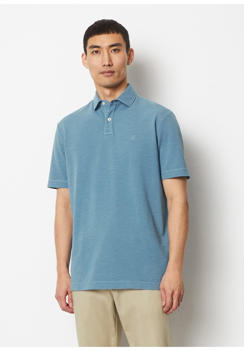 Blue polo shirt made of textured fabric, featuring a collar, two buttons, and a small logo on the chest. Short sleeves and standard fit.