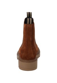 Bruna mockaskinnankleboots med en strukturerad yta och en kontrasterande tanfärgad gummisula. Har en randig dragflik på baksidan.