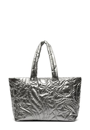 Sac cabas matelassé argenté brillant avec deux anses rembourrées et motifs abstraits cousus sur fond blanc.
