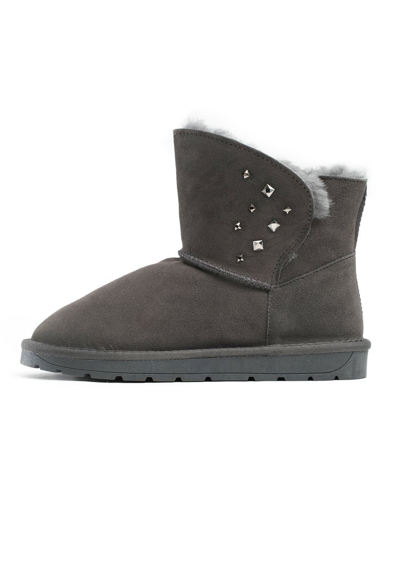 Stivale alla caviglia in suede grigio con punta rotonda, foderato in pelliccia sintetica e decorato con borchie argento sul lato esterno. Suola piatta in gomma con trazione.