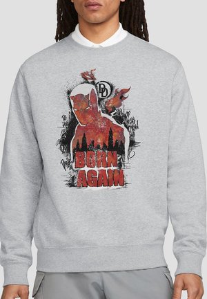Gray sweatshirt featuring a graphic of a character with a red and black design. Text reads "BORN AGAIN." Fabric appears soft with ribbed cuffs.