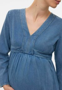 Modra denim obleka za nosečnice z V-izrezom, dolgimi rokavi in detajlom z nabiranjem v pasu, z vidnimi šivi.