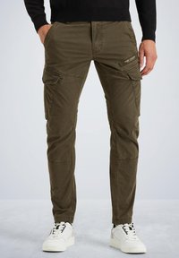 Maslinasto zelene cargo hlače s teksturiranom tkaninom, višestrukim bočnim džepovima i slim fit dizajnom, u kombinaciji s bijelim tenisicama.