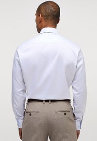 Witte langemouw shirt met een klassieke kraag, gladde textuur en knoopmanchetten. Draag met lichtbruine broek met zijzakken.
