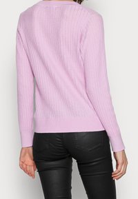 Maglione a coste rosa chiaro con maniche lunghe e vita aderente. Presenta un collo semplice e polsini aderenti, realizzato in un morbido tessuto a maglia.