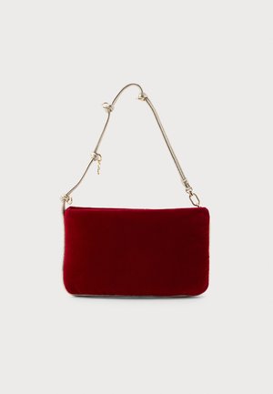 Bolsa retangular de veludo vermelho profundo com uma alça metálica fina, apresentando nós decorativos e hardware em tom dourado.