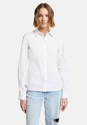 Witte button-up shirt van katoen met lange mouwen en een kraag. Slim fit, met een rechte zoom en achterste plooien. Gemaakt in combinatie met lichtblauwe gescheurde jeans.