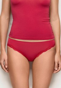 Top in cotone rosso misto abbinato a mutandine rosse con pizzo, caratterizzato da una morbida texture e un design aderente.
