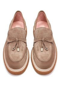 Paire de mocassins en daim marron clair avec pompons et semelles épaisses en crêpe, vue de dessus sur fond blanc.