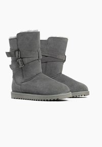 Botas de tobillo de ante gris con un suave forro de piel sintética, que cuentan con dos correas ajustables y una suela de goma con un agarre texturizado.
