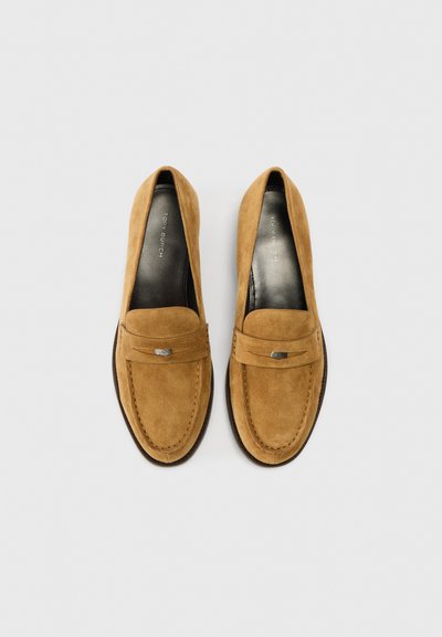 Barna szarvasbőr mokaszin sima felülettel, varrott orr-résszel és ezüst díszítésű dekoratív pánttal. Lapos talp.