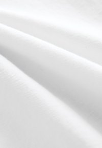 Tissu blanc lisse avec des plis subtils et une texture douce, montrant les détails d'un tissage fin.