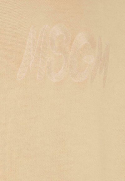 Tessuto di cotone beige con una consistenza morbida, caratterizzato da un logo impresso "MSGM" in una tonalità leggermente più chiara.