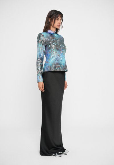 Blusa de manga longa, multicolorida, com um padrão em espiral em tons de azul, combinada com uma saia preta de cetim elegante. Calçado prateado brilhante completa o visual.