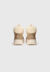Botas de color marrón claro con un suave cuello de piel de crema, material de ante, suela resistente y un pequeño lazo en la parte trasera para facilitar su uso.