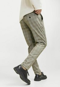 Lichtgroene geruite broeken met een slim fit, voorzien van zijzakken en een achterste knoopdetail, gecombineerd met zwarte veterschoenen.