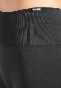 Leggings neri con vita a coste e texture liscia. L'etichetta "SMILODOX" è visibile nella parte superiore.