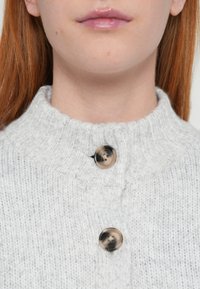 Szary sweter dzianinowy z wysokim kołnierzem i dwoma okrągłymi, jasnobrązowymi guzikami, prezentujący teksturowany wzór i miękki, przytulny wygląd.