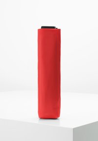 Red cylindrical umbrella with a smooth fabric cover, a black handle at the top, and a simple design without patterns or embellishments.