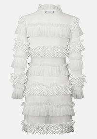 Robe blanche ornée de volants superposés en tissu transparent et de délicates garnitures en dentelle. Manches longues avec poignets élastiques. Encolure haute.