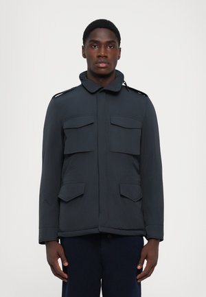 Men's dark navy jacket with a high collar, four front pockets, shoulder epaulets, and a smooth, lightweight texture.