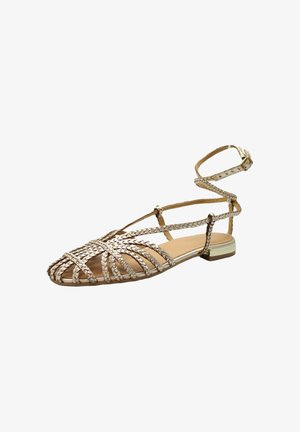 Sandalo piatto intrecciato color oro metallizzato con punta affilata, cinturino avvolgente alla caviglia e tacco basso.