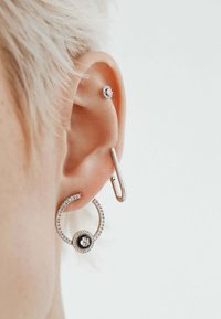 Los pendientes de aro de plata presentan un diseño en espiral adornado con pequeñas piedras de cristal transparentes y una piedra negra central, junto con un pendiente metálico de stud.