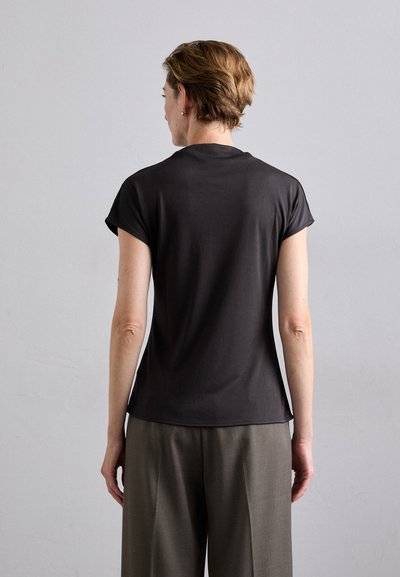 Dark gray short-sleeve t-shirt with a smooth texture, rounded neckline, and a relaxed fit, paired with light gray tailored trousers.