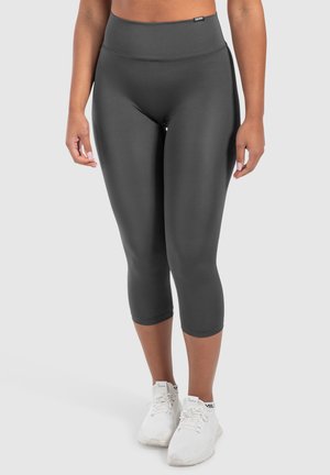Leggings capri grigi, aderenti, con vita alta e materiale liscio, abbinati a scarpe da ginnastica bianche.