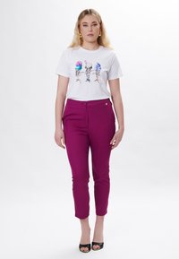 Hvid kortærmet t-shirt med farverig is-skimling; parret med tætsiddende lilla bukser og sorte sandaler med åben tå.